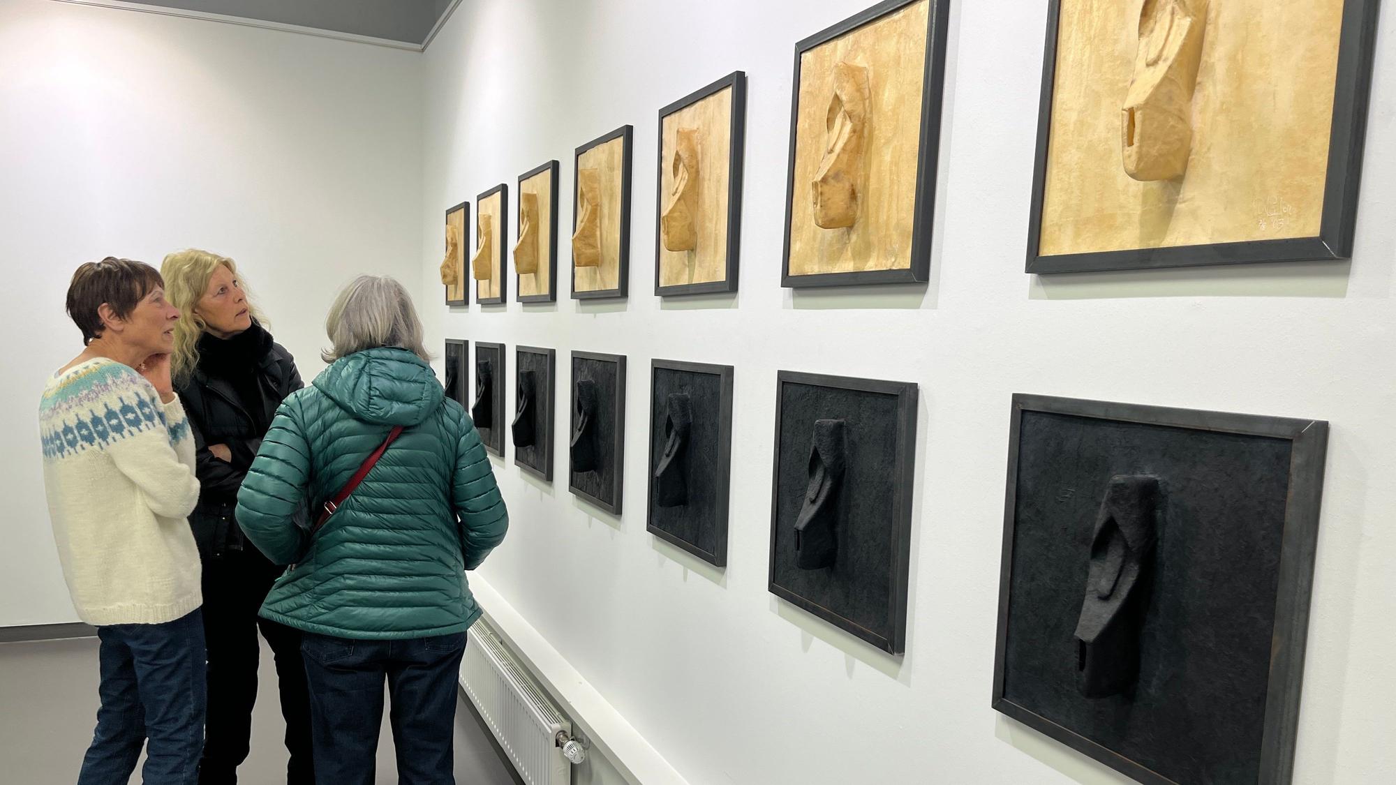 Besucher einer Ausstellung schauen sich Kunstwerke an.