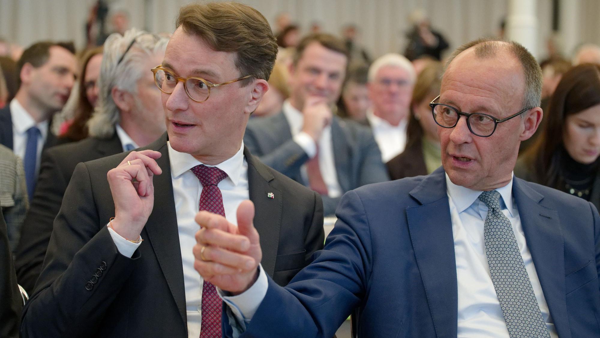 Hendrik Wüst (l, CDU), Ministerpräsident von Nordrhein-Westfalen, und Friedrich Merz, Vorsitzender der CDU, sitzen bei einer Veranstaltung nebeneinander.