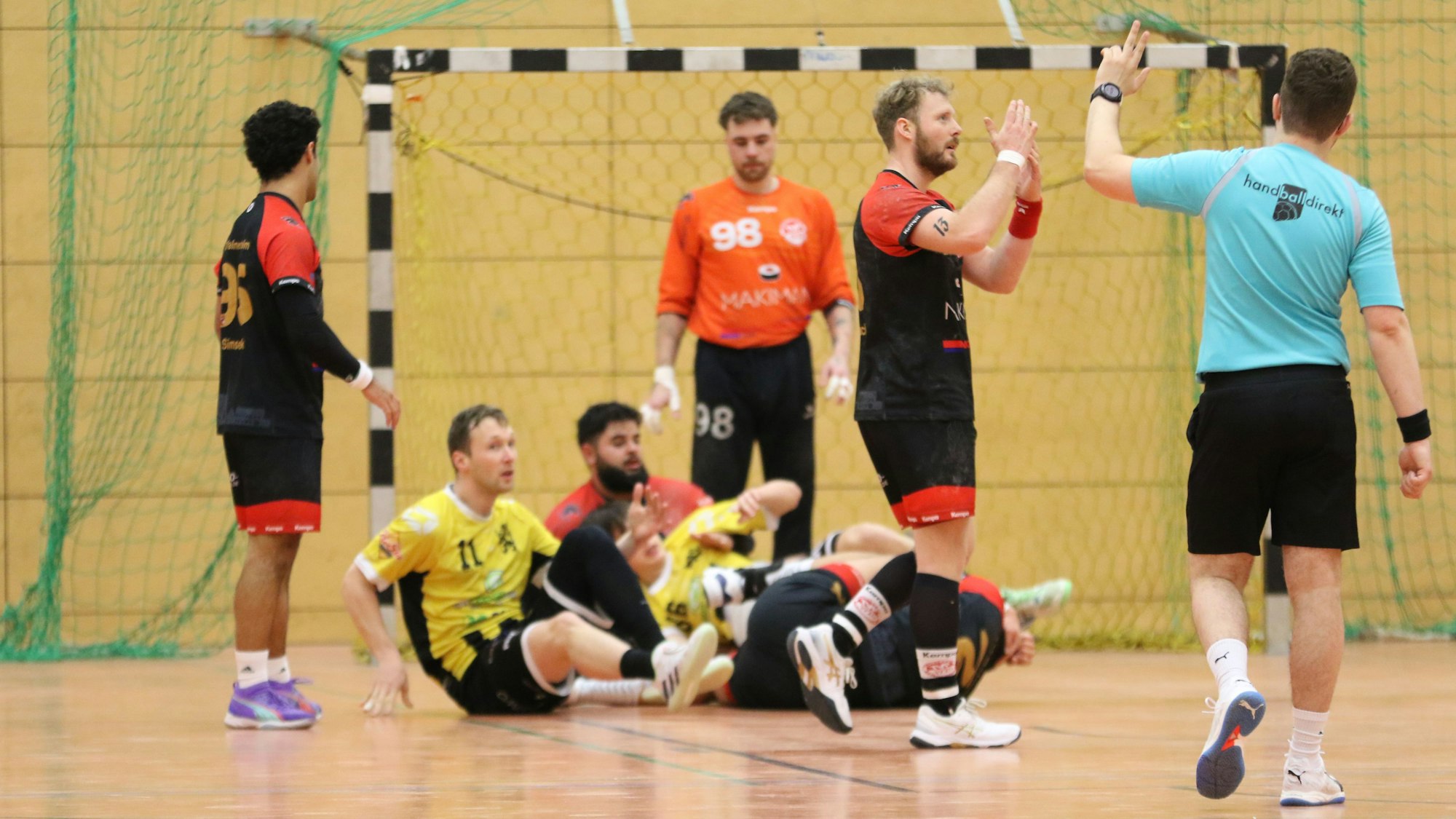 Vier Spieler liegen im Kreis der Palmersheimer, René Lönenbach gestikuliert, der Schiedsrichter hebt zwei Finger