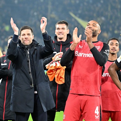 Leverkusens Edmond Tapsoba (l-r), Trainer Xabi Alonso und Jonathan Tah feiern den Sieg in Dortmund.