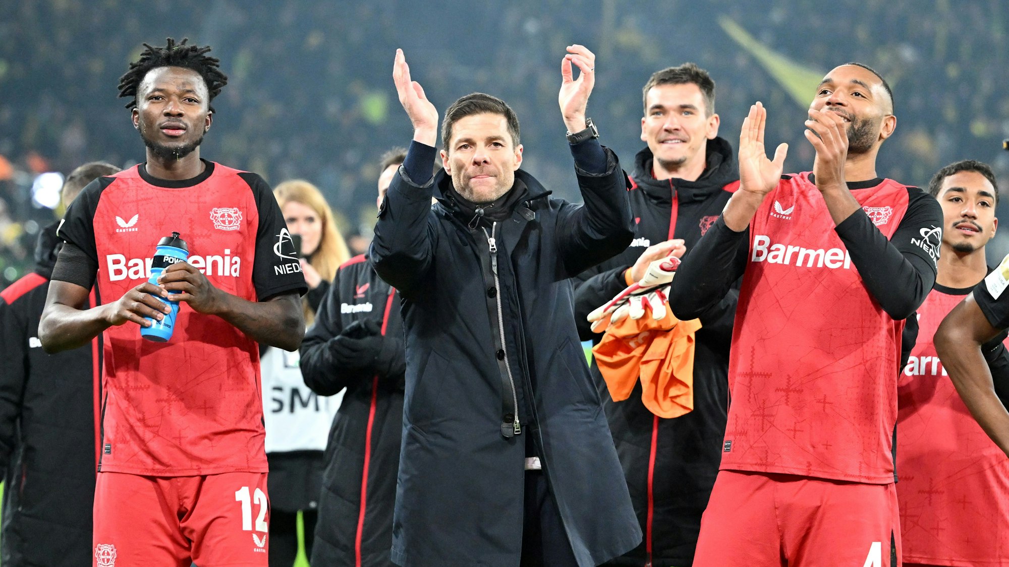 Leverkusens Edmond Tapsoba (l-r), Trainer Xabi Alonso und Jonathan Tah feiern den Sieg in Dortmund.
