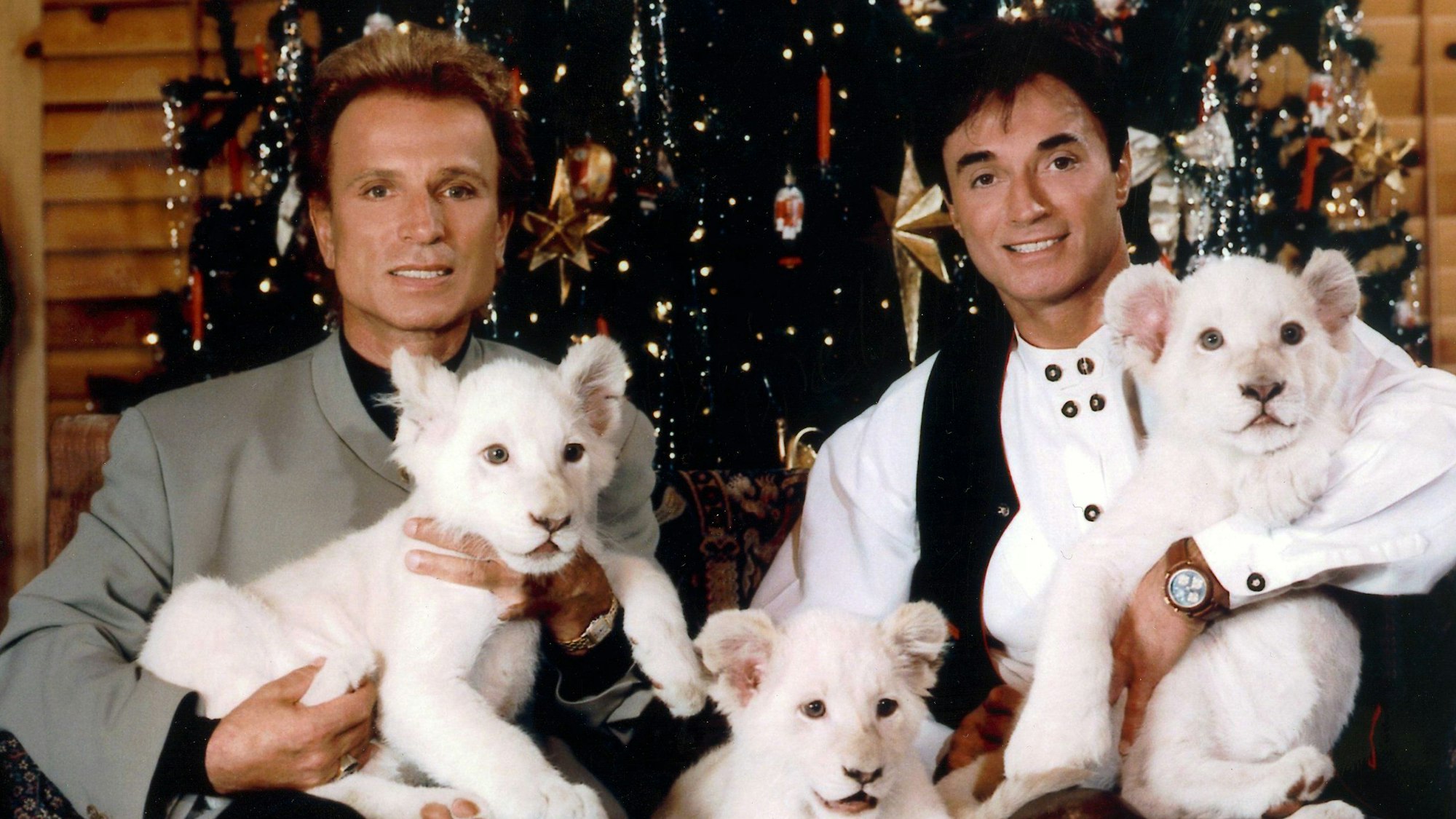 Die deutschen Magier Siegfried (l) und Roy sitzen vor einem Weihnachtsbaum.