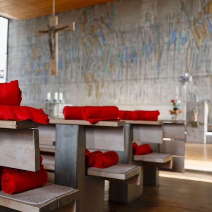 In einer Kirche liegen rote Decken auf den Bänken für die Gläubigen bereit.