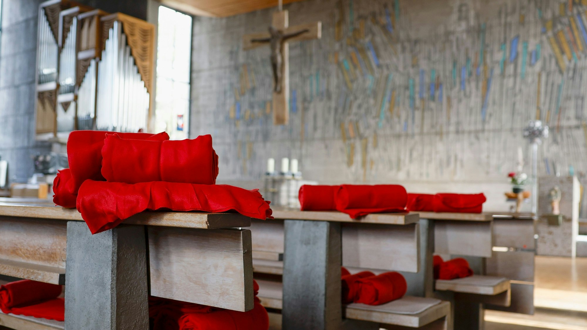 In einer Kirche liegen rote Decken auf den Bänken für die Gläubigen bereit.