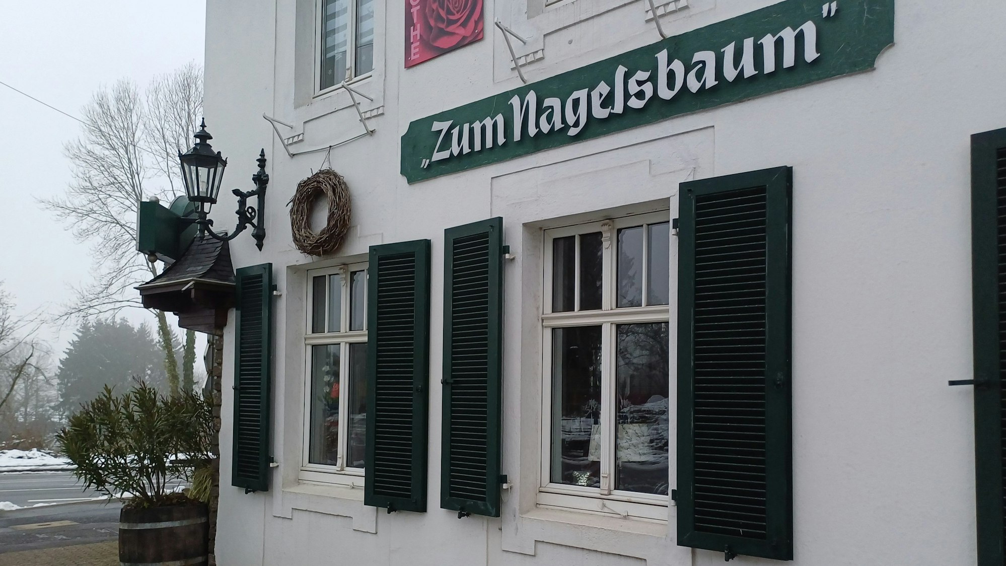 Ein Schild mit der Aufschrift „Zum Nagelsbaum“ hängt an einem Haus.