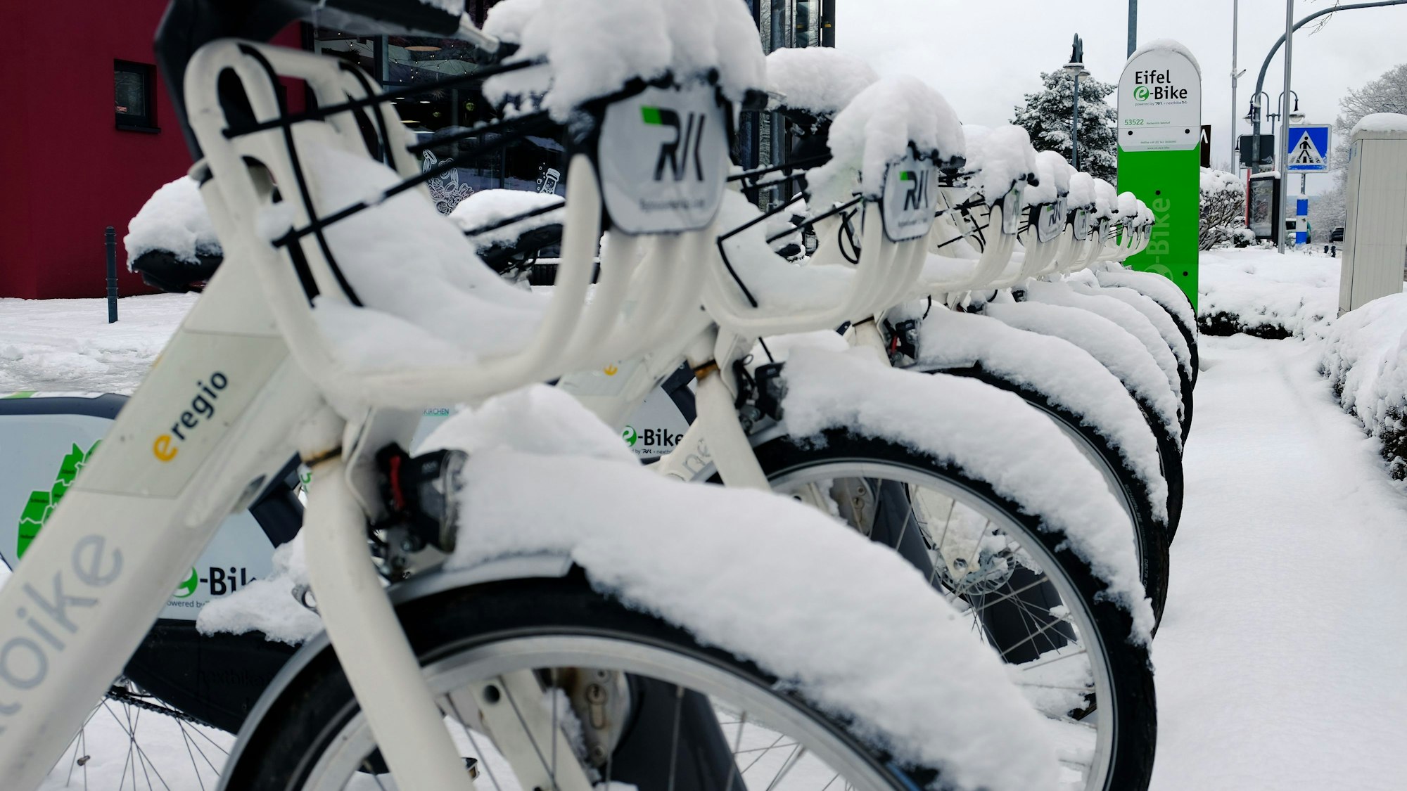 Vor dem Bahnhof in Mechernich stehen schneebedeckte Eifel e-Bikes.