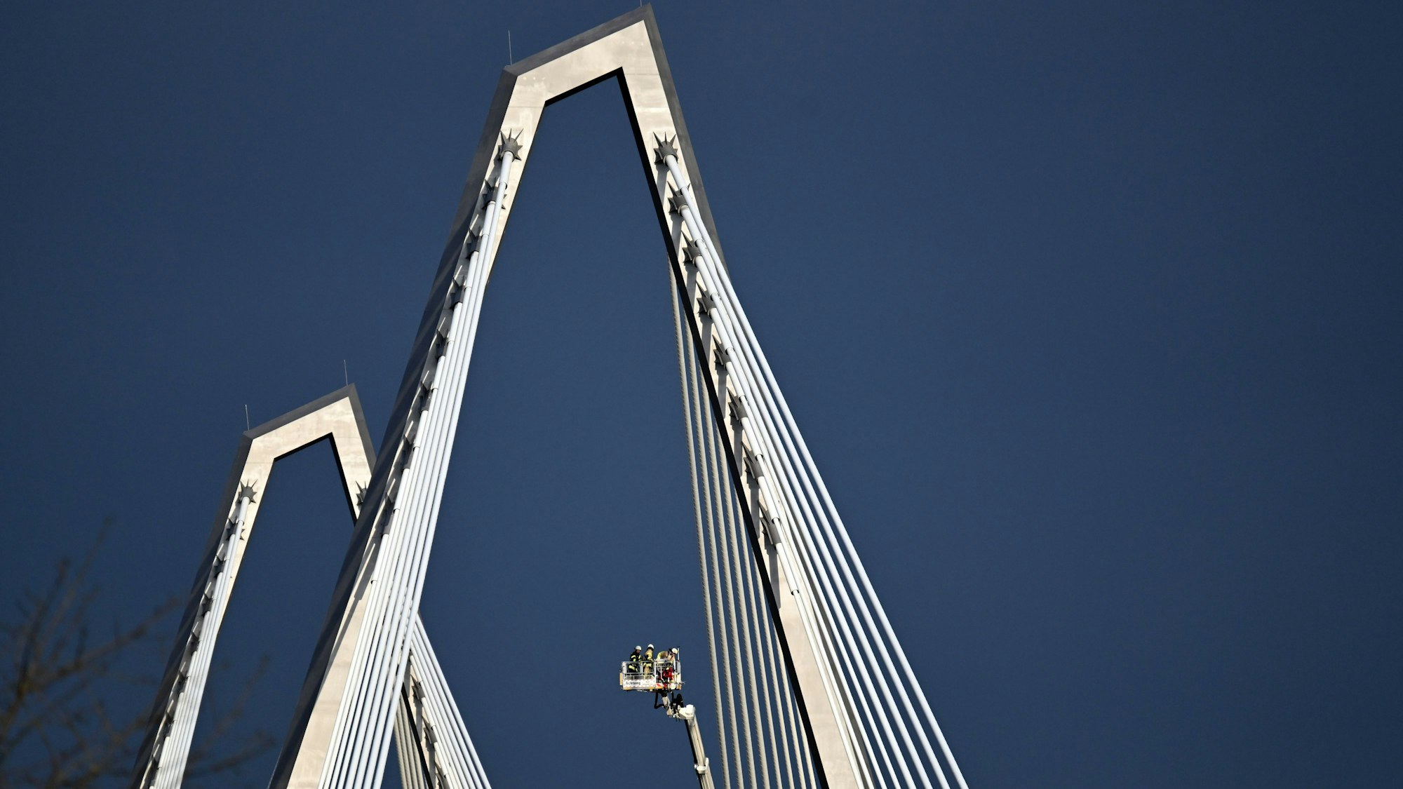 Einsatzkräfte lassen sich mit einem Hubwagen zu den Spitzdächern einer der zwei Pylone der Leverkusener Rheinbrücke hochfahren (Archivfoto).