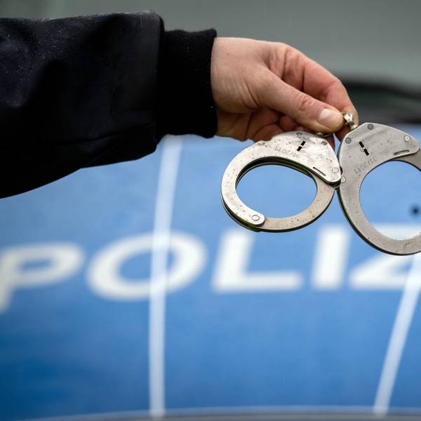 Ein Polizist hält ein Paar Handschellen.