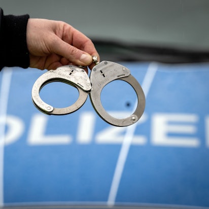 Ein Polizist hält ein Paar Handschellen.