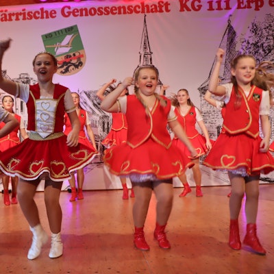 Mädchen in roten Kleidern tanzen auf einer Bühne.