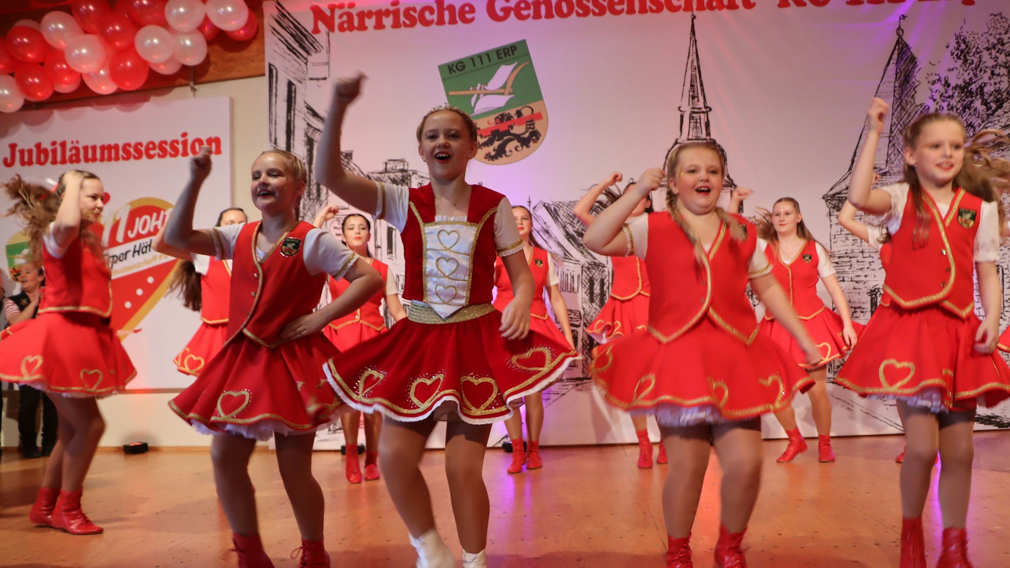 Mädchen in roten Kleidern tanzen auf einer Bühne.