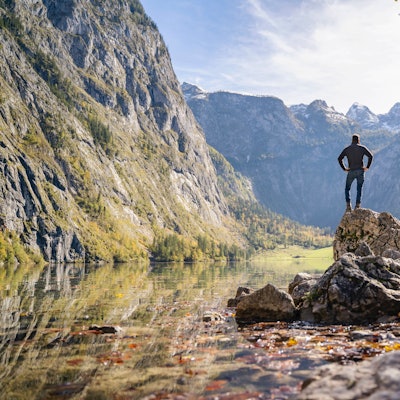 Mann steht auf einem Felsen in der Nähe des Obersees und der Berge in Berchtesgaden.