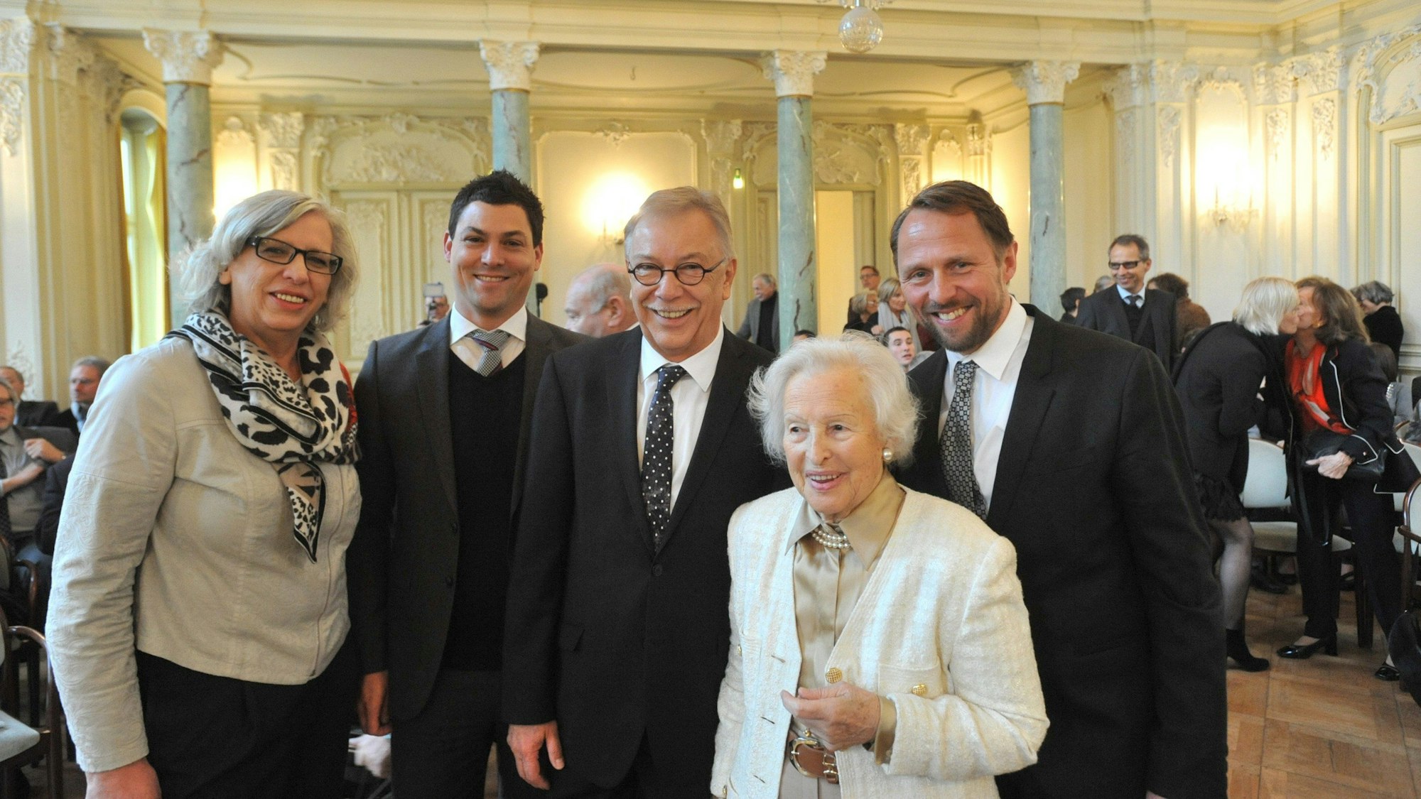 Zwei Frauen und drei Männer lächeln auf einem Gruppenfoto in die Kamera.