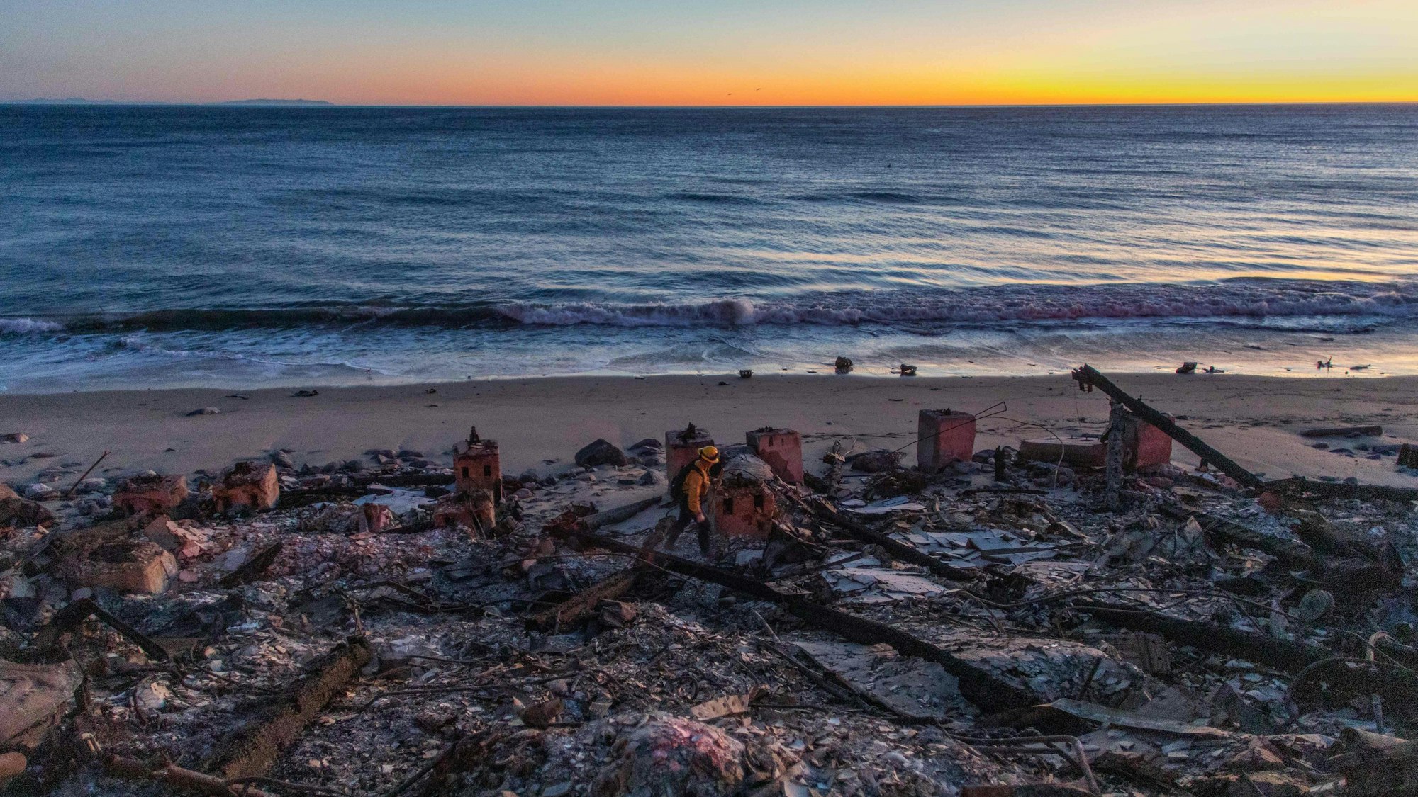 Ein Feuerwehrmann geht durch verbrannte Ruinen eines Hauses am Strand von Kalifornien.