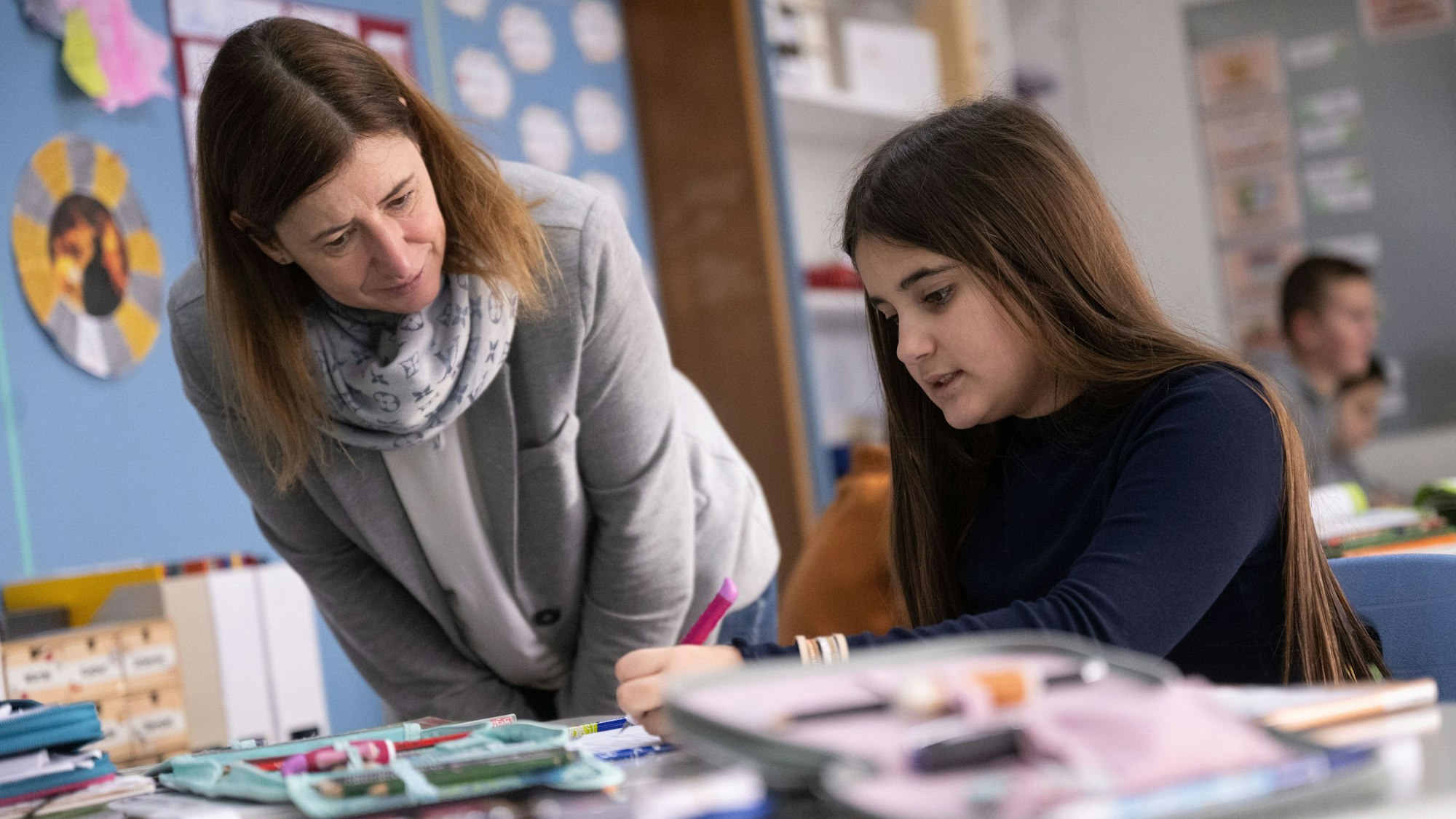 Eine Lehrerin unterstützt eine Schülerin im Unterricht.