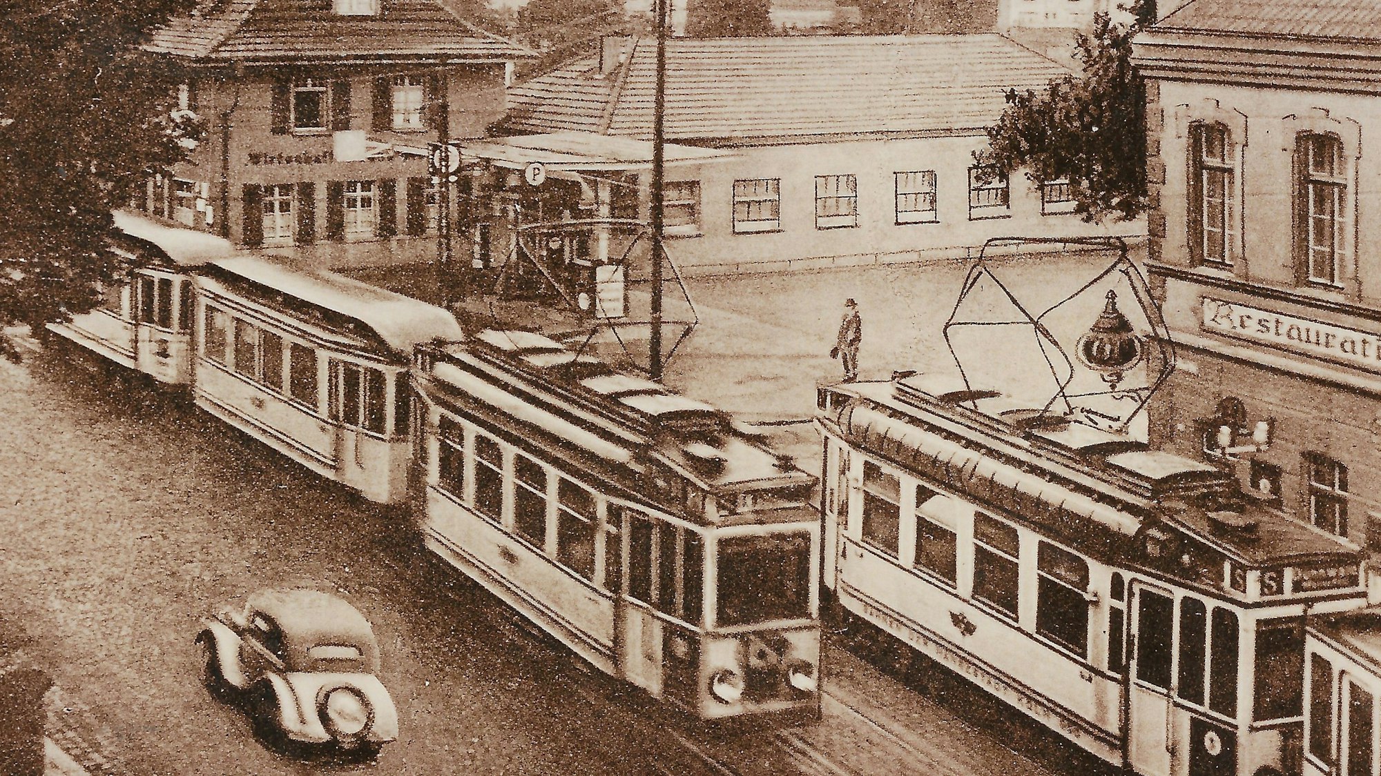 Zu sehen ist die Ecke Berliner Straße und Odenthaler Straße ca. 1939 mit einem Auto und Straßenbahn auf einer Schwarzweißfotografie.