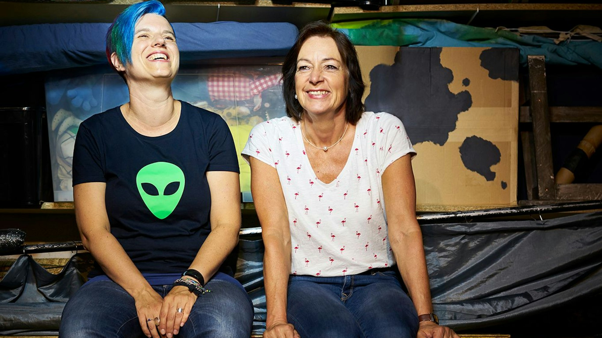 Zwei Frauen sitzen am Rande einer Bühne.