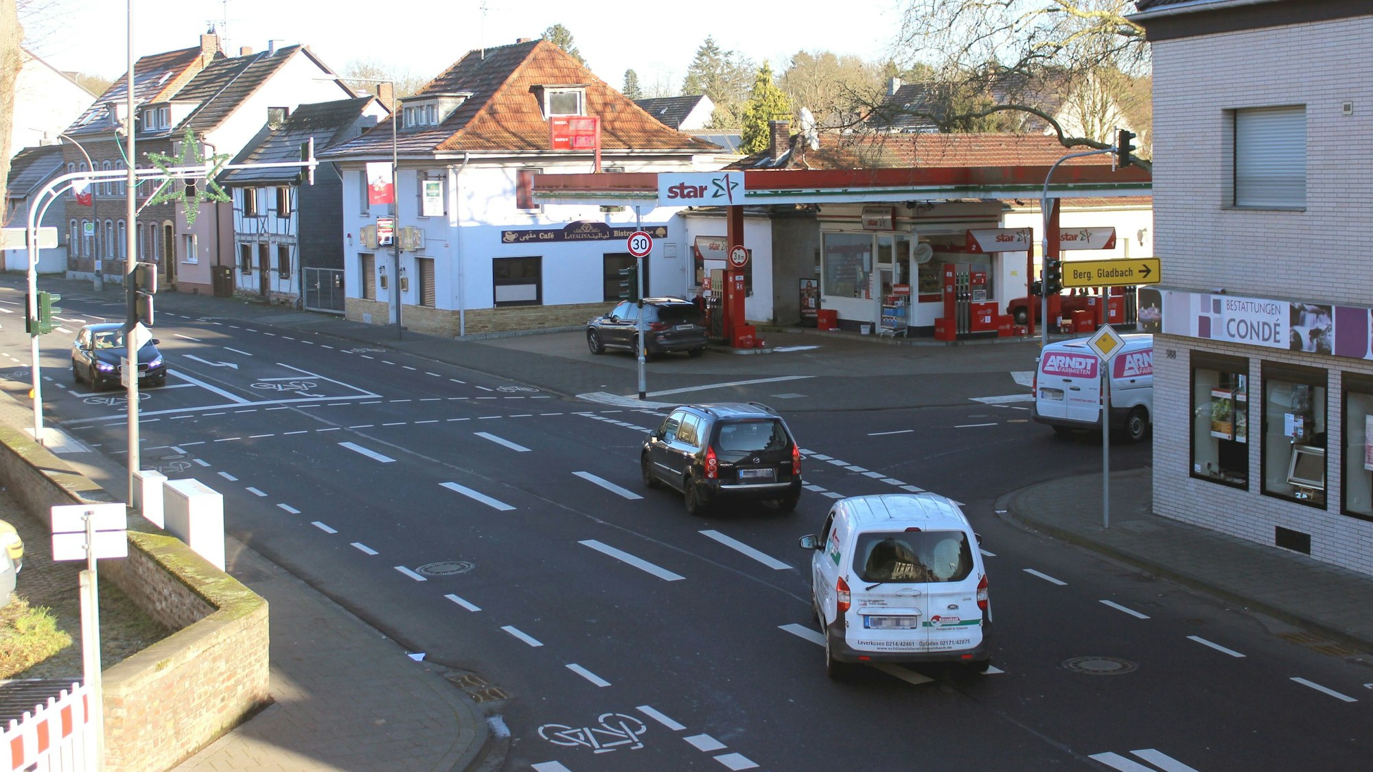 Zu sehen sind eine Straße, Häuser, Autos und eine Tankstelle.