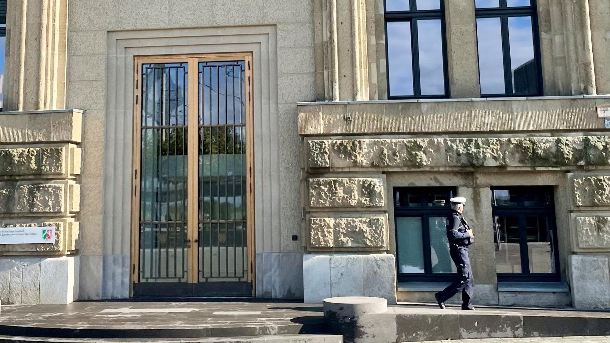 ARCHIV - 10.10.2024, Nordrhein-Westfalen, Düsseldorf: Ein Polizist geht am neuen sogenannten repräsentativen Eingang der Staatskanzlei entlang. (zu dpa: «Razzien: Korruption bei Sanierung der Staatskanzlei?») Foto: Oliver Auster/dpa +++ dpa-Bildfunk +++