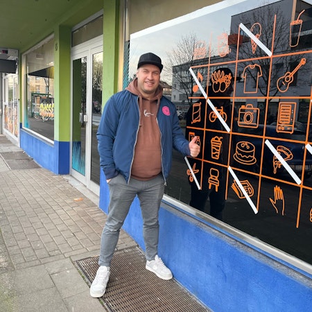 Mann vor Ladenlokal.