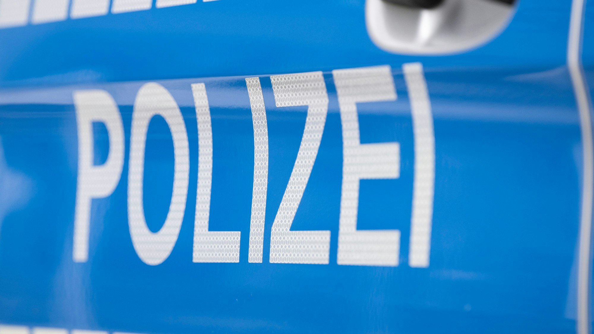 Das Foto zeigt den Schriftzug „Polizei“ auf einem Streifenwagen.