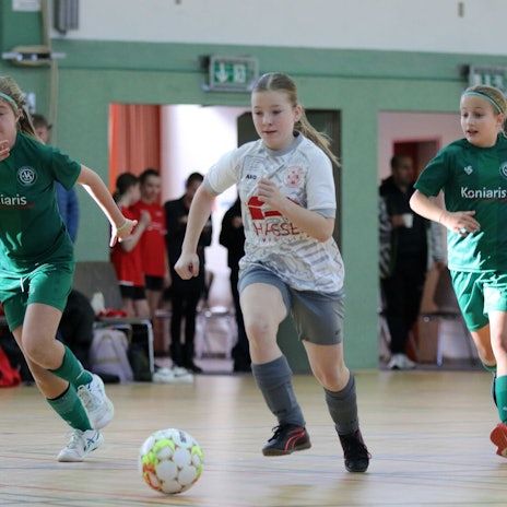 Eine Zülpicher Spielerin führt den Ball und wird von zwei Gegenspielerinnen flankiert.