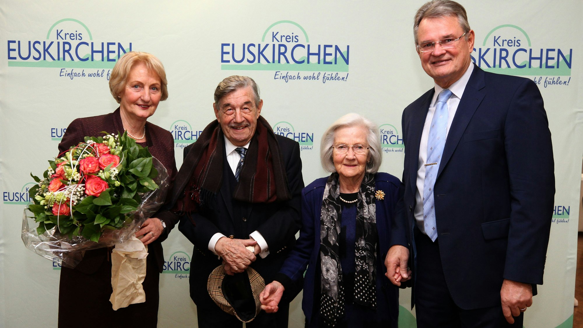 In der Bildmitte sind Victor und Annelene Neels zu sehen, rechts und links Karin und Günter Rosenke. Im Hintergrund ist eine Wand mit dem Schriftzug „Kreis Euskirchen“.