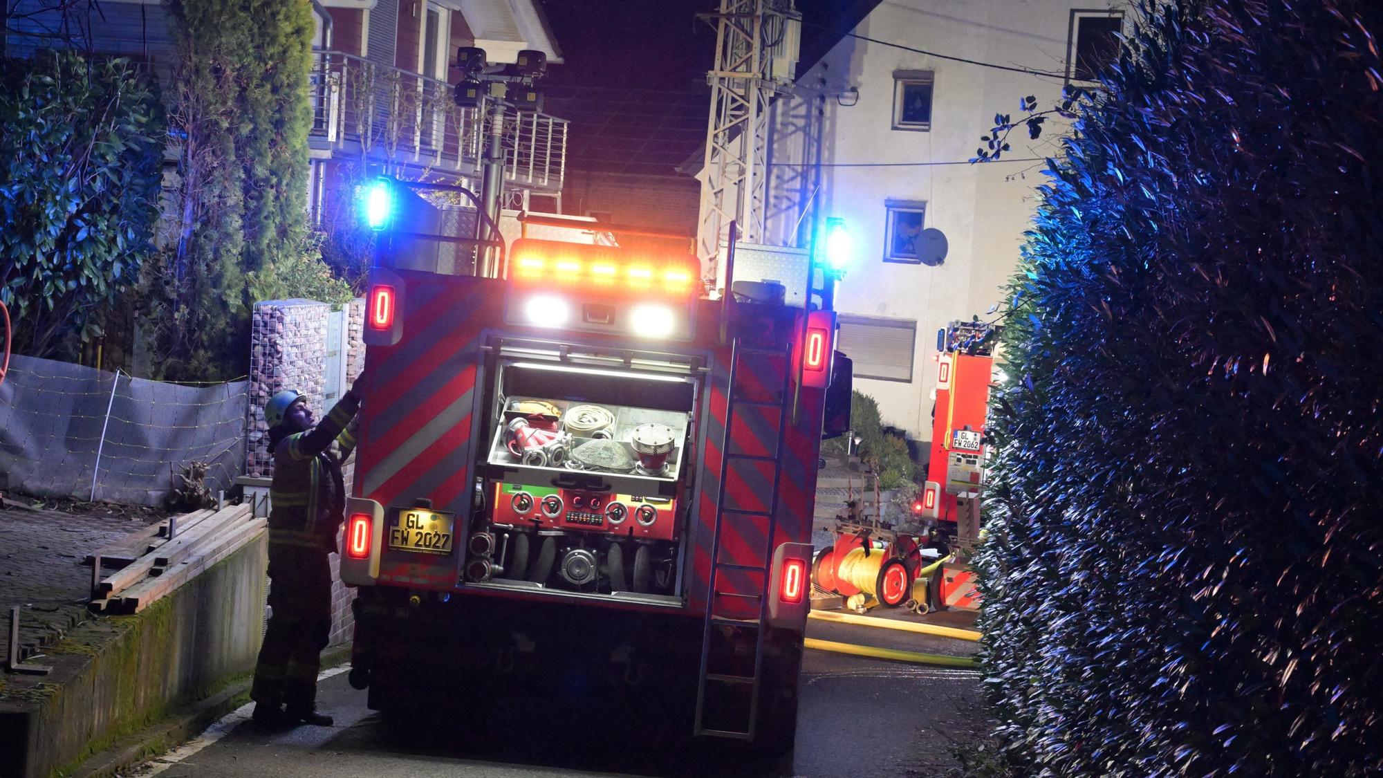 Ein Feuerwehrfahrzeug steht vor einem Brandhaus in Bergisch Gladbach-Voislöhe.