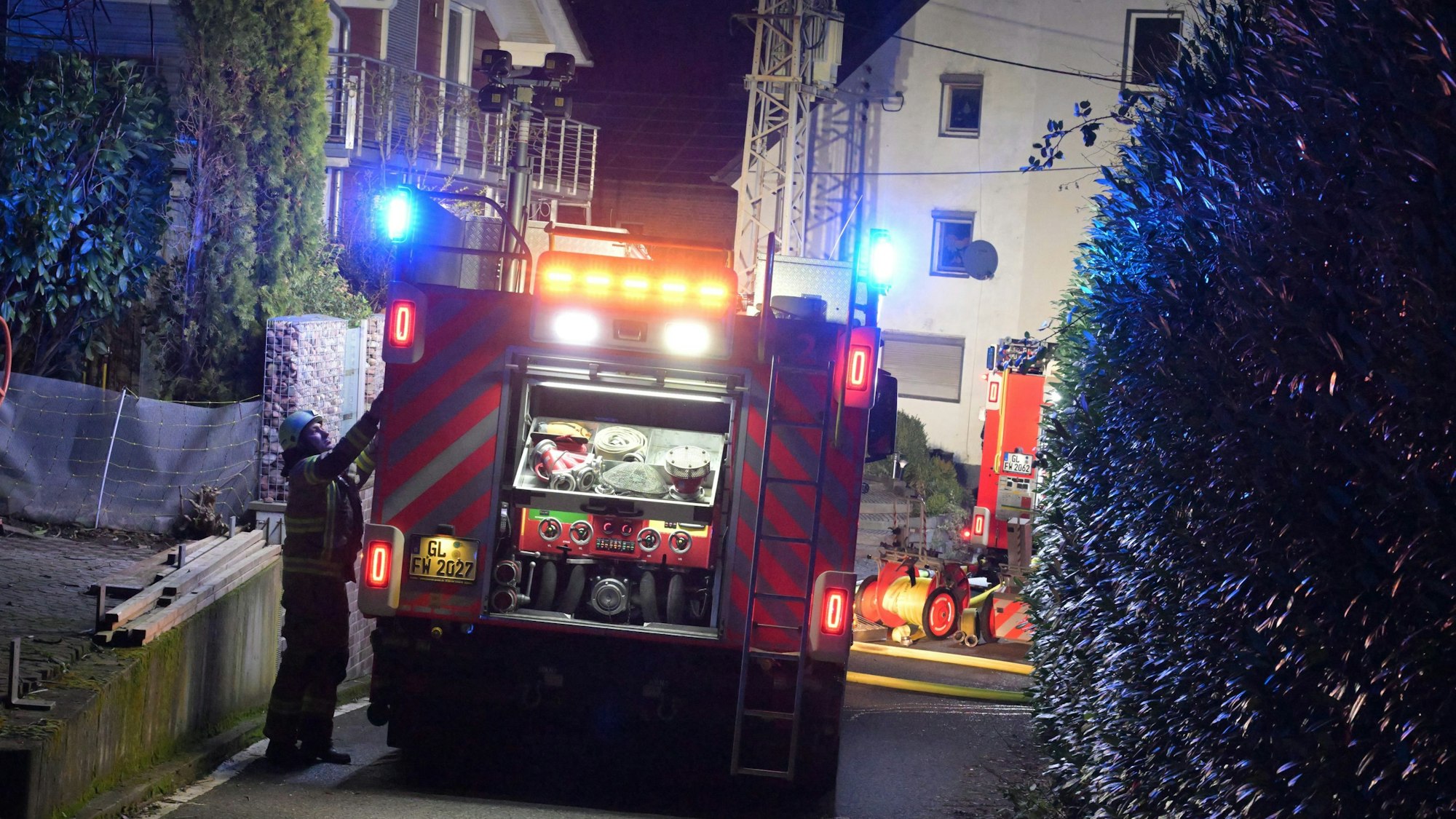 Ein Feuerwehrfahrzeug steht vor einem Brandhaus in Bergisch Gladbach-Voislöhe.