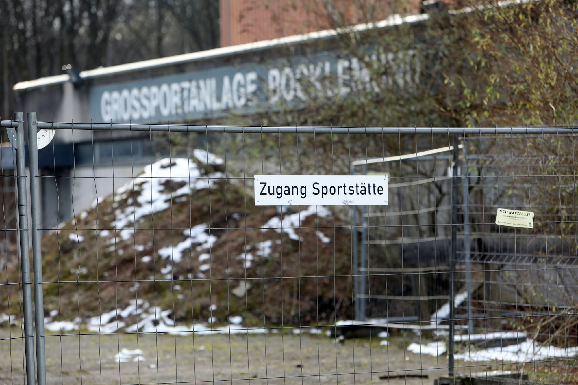 Außenansicht der Bezirkssportanlage Bocklemünd mit Blick auf einen Bauzaun.