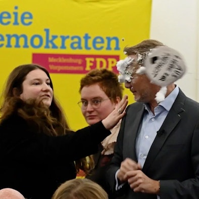 Mecklenburg-Vorpommern, Greifswald: Der FDP-Vorsitzende Christian Lindner bekommt bei einem Wahlkampfauftritt in Greifswald von der Linke-Lokalpolitikerin Christiane Kiesow (l) Schaum ins Gesicht geworfen.