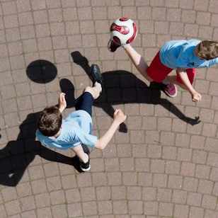Kinder spielen Fußball auf einem Schulhof.