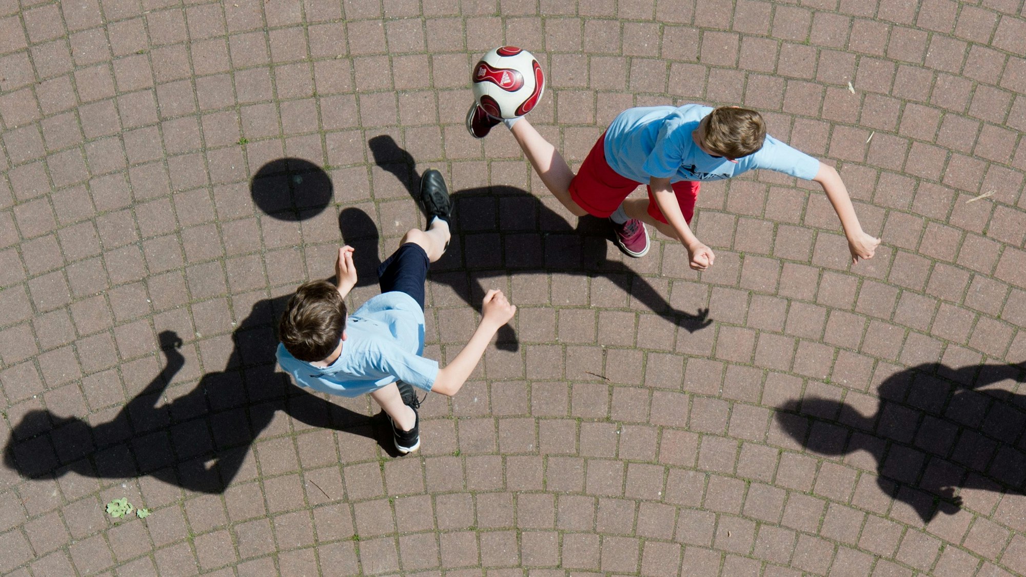 Kinder spielen Fußball auf einem Schulhof.