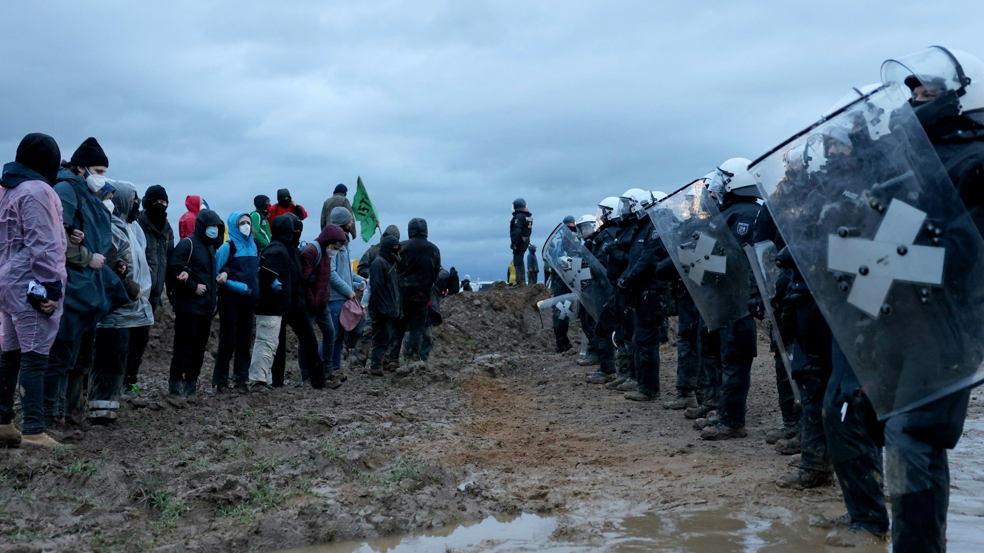 Polizisten und Demonstranten stehen sich bei der Demonstration von Klimaaktivisten am Rande des Braunkohletagebaus bei Lützerath gegenüber.