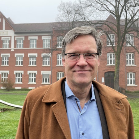 Ein Mann steht vor einem Gebäude.