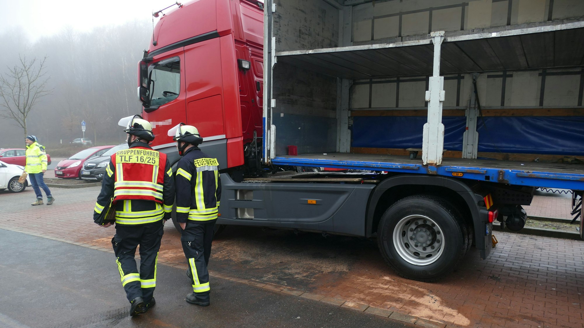 Feuerwehrleute stehen vor der abgestreuten Diesel-Pfütze des Lkws.