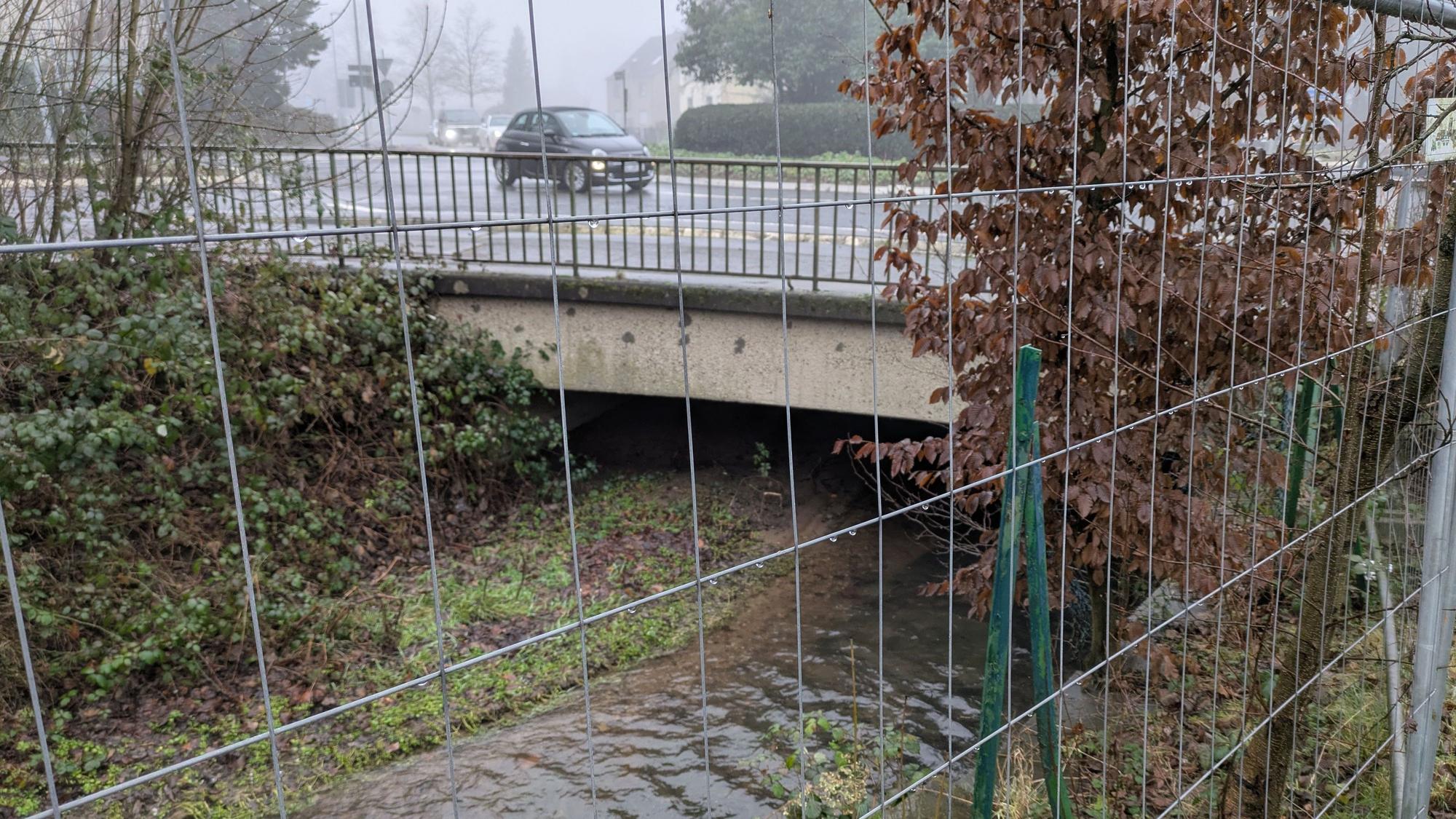 Ein Bach fließt unter einer Straße hindurch.