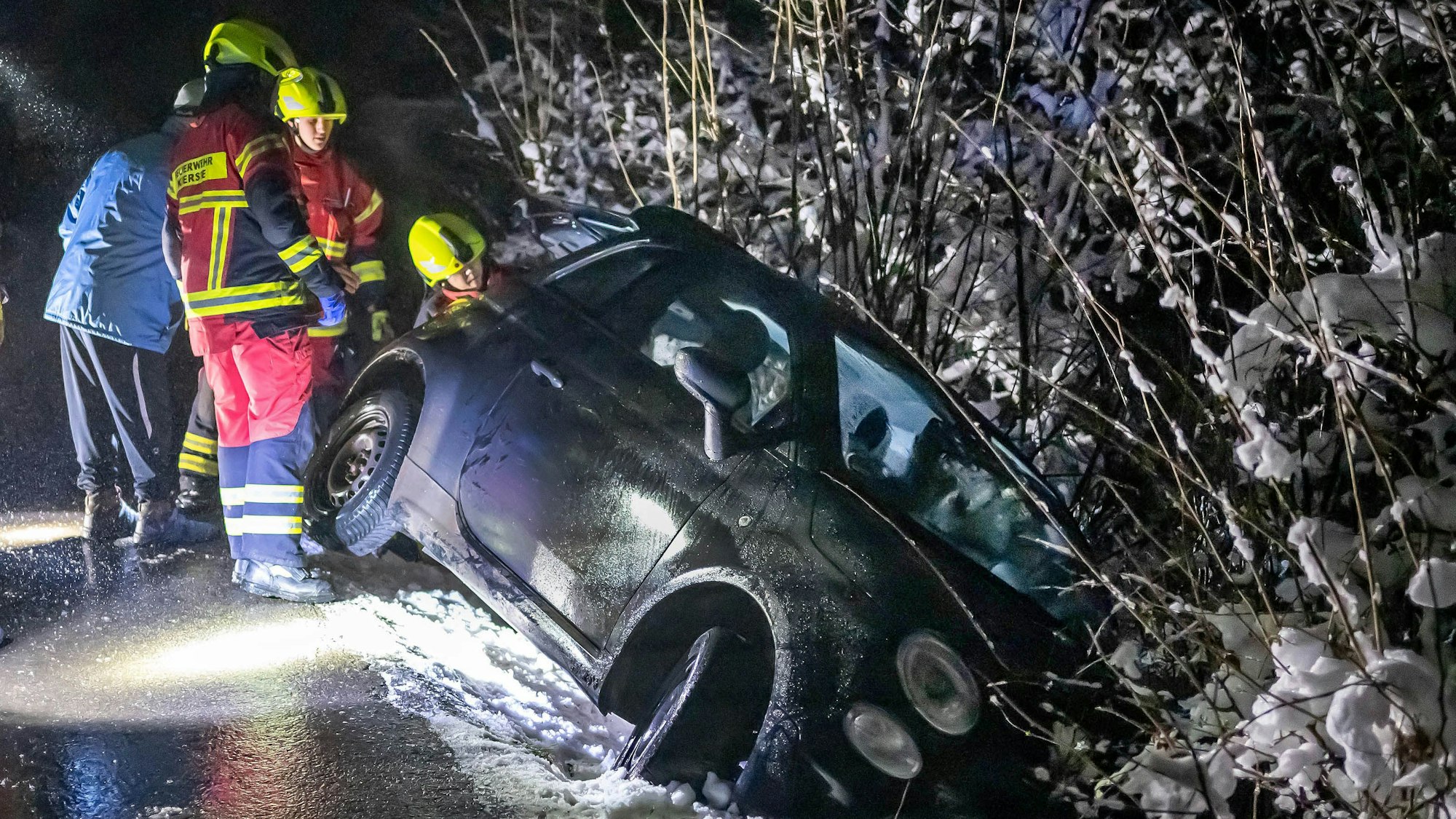 dpatopbilder - 14.01.2025, Nordrhein-Westfalen, Kierspe: Ein Kleinwagen ist bei Straßenglätte im westlichen Sauerland in einen Graben gerutscht und Helfer sind im Einsatz. Verletzt wurde niemand. Auf glatten Straßen hat es im Sauerland mehrere Unfälle gegeben. Foto: Markus Klümper/dpa - ACHTUNG: Kennzeichen wurde aus rechtlichen Gründen gepixelt +++ dpa-Bildfunk +++