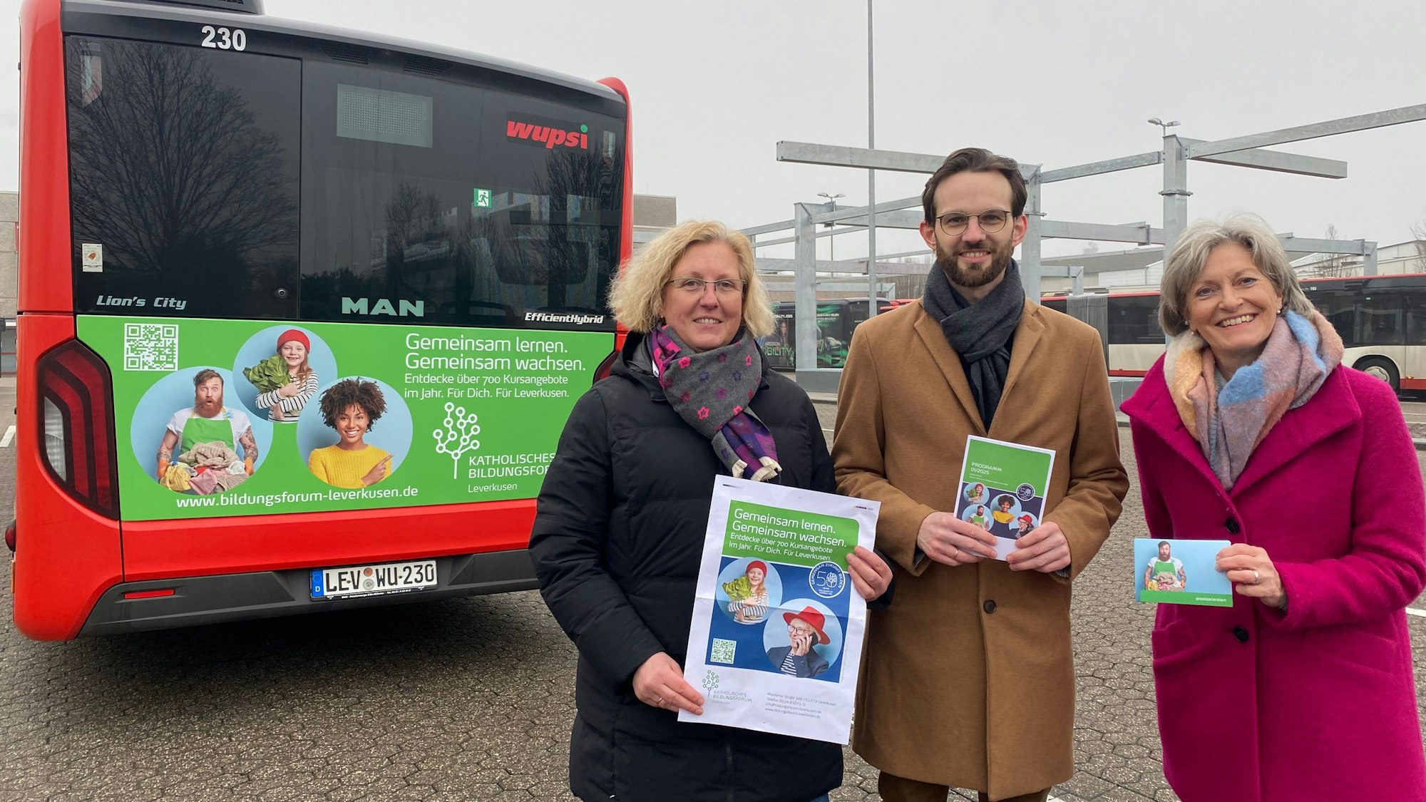 Leiterin Sabine Höring mit Maximilian Anton und Martina Böhm vom Katholischen Bildungsforum vor einem Bus mit Werbung von ihnen