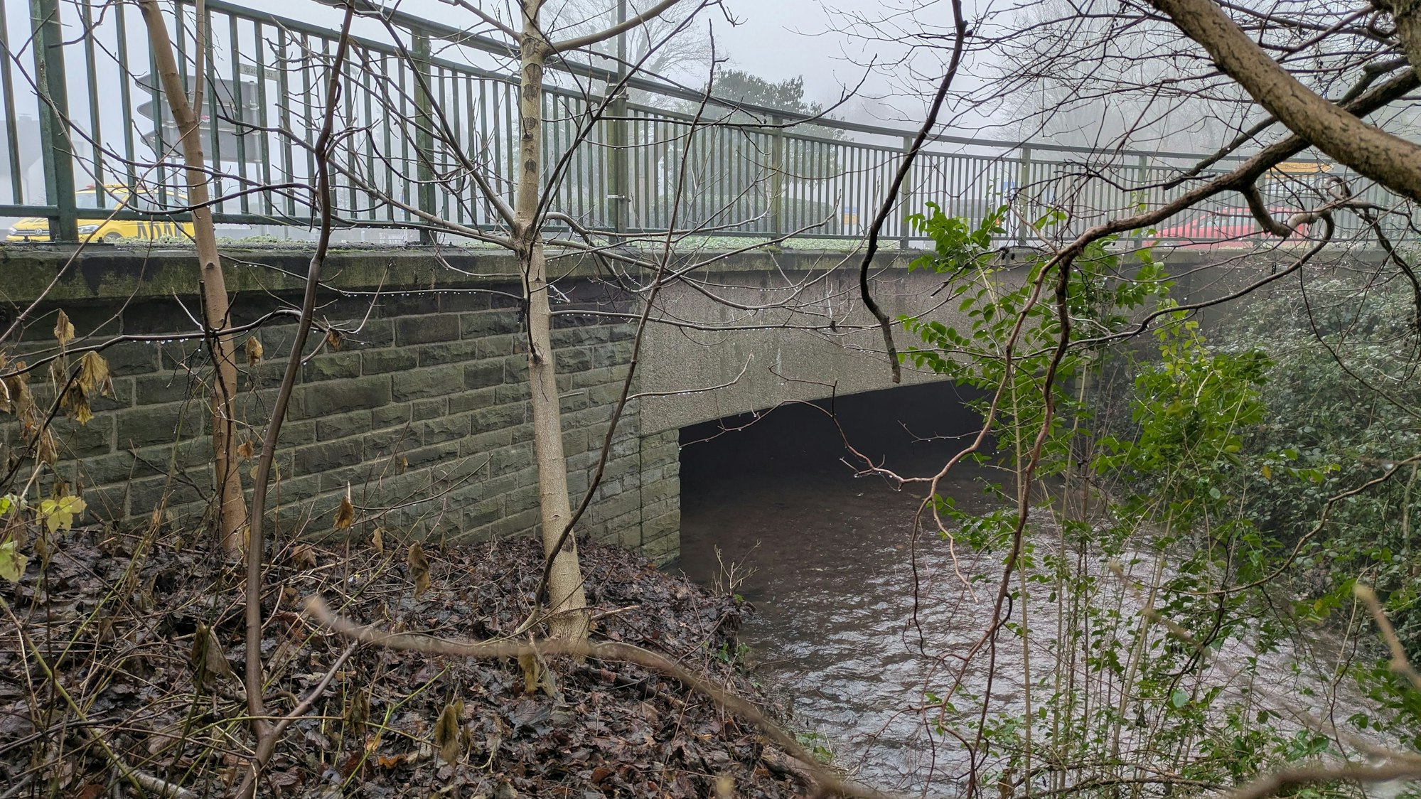 Ein Bach fließt unter einer Brücke hindurch.