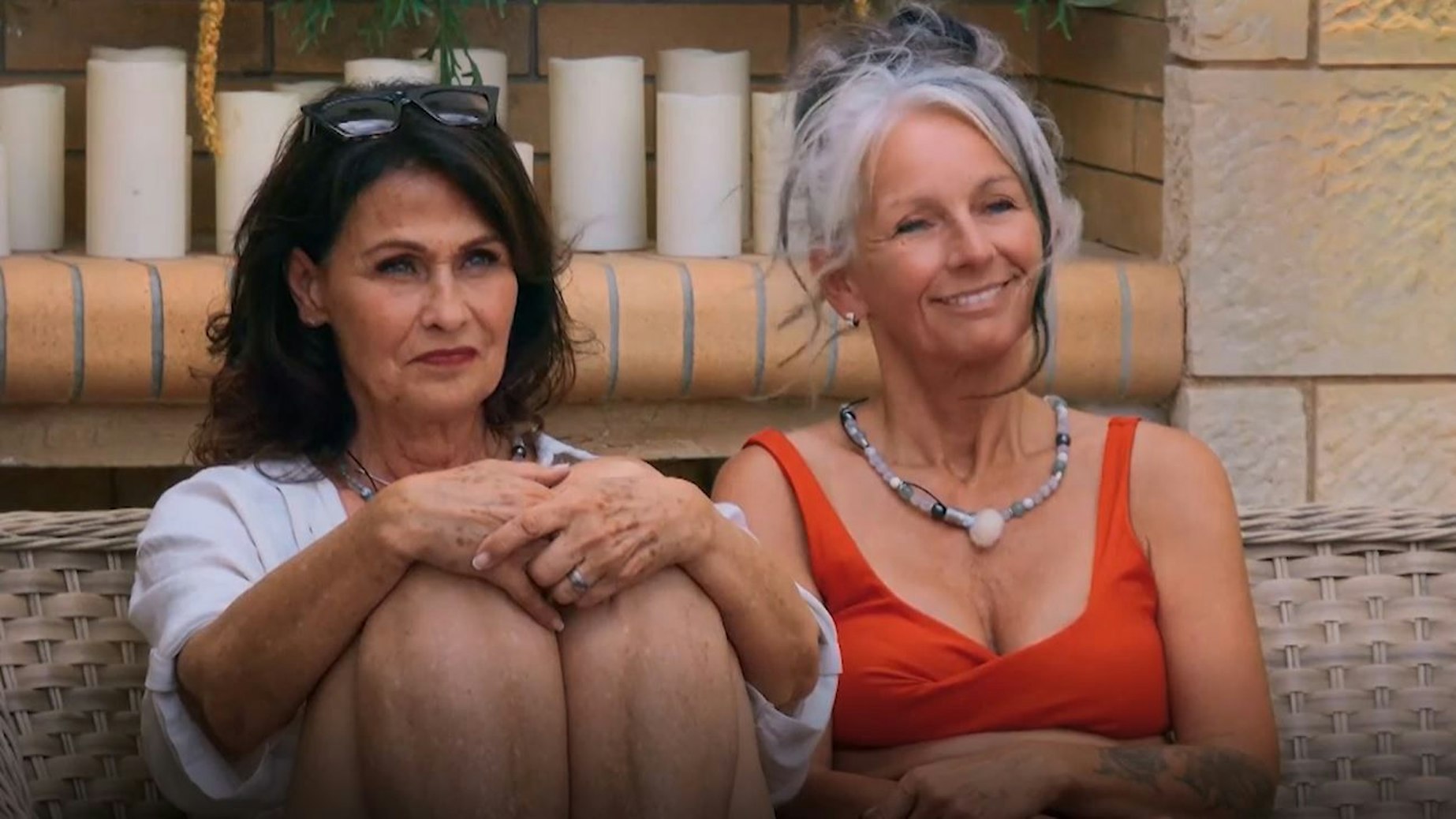 Sabine (r.) lacht rechts an der Kamera vorbei. Links neben ihr sitzt eine Frau auf einer Bank.