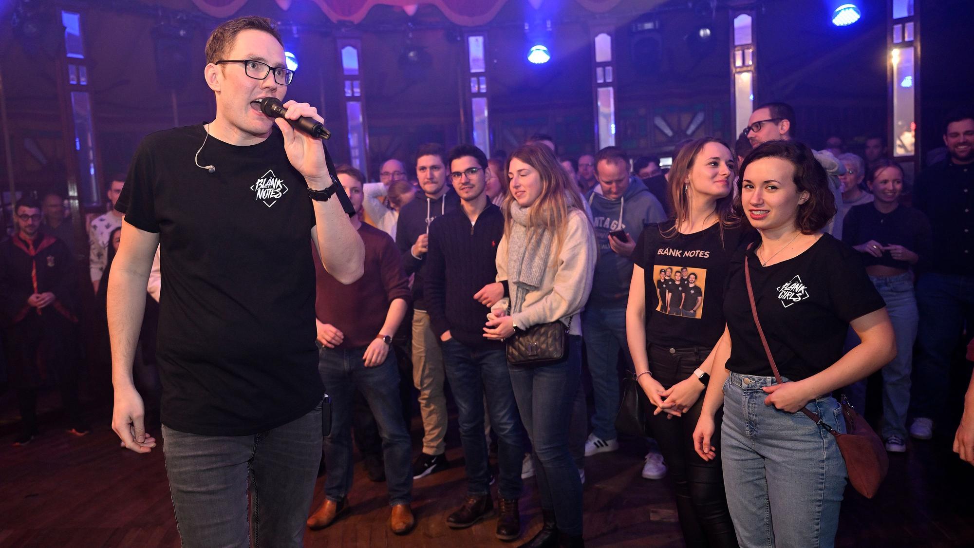 Ein Sänger mit einem Mikro steht vor Publikum im Altenberger Spiegelzelt und singt.