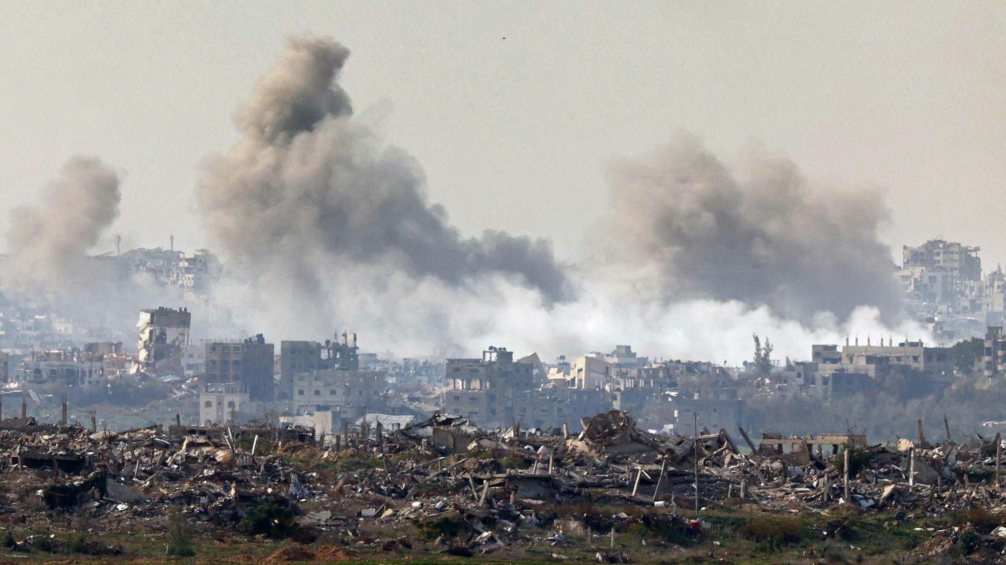 This picture taken from the Israeli side of the border with the Gaza Strip shows smoke plumes rising from explosions above destroyed buildings in the northern Gaza Strip on January 14, 2025, amid the ongoing war between Israel and Hamas. (Photo by Jack GUEZ / AFP)