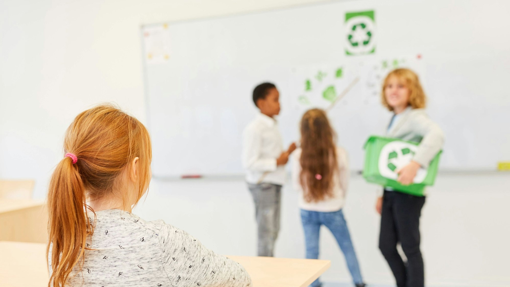 Schüler*innen in der Grundschule halten ein Referat über Recycling und Umweltschutz.