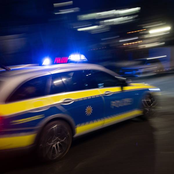 Ein Polizeifahrzeug fährt mit Blaulicht an einem Gebäude vorbei