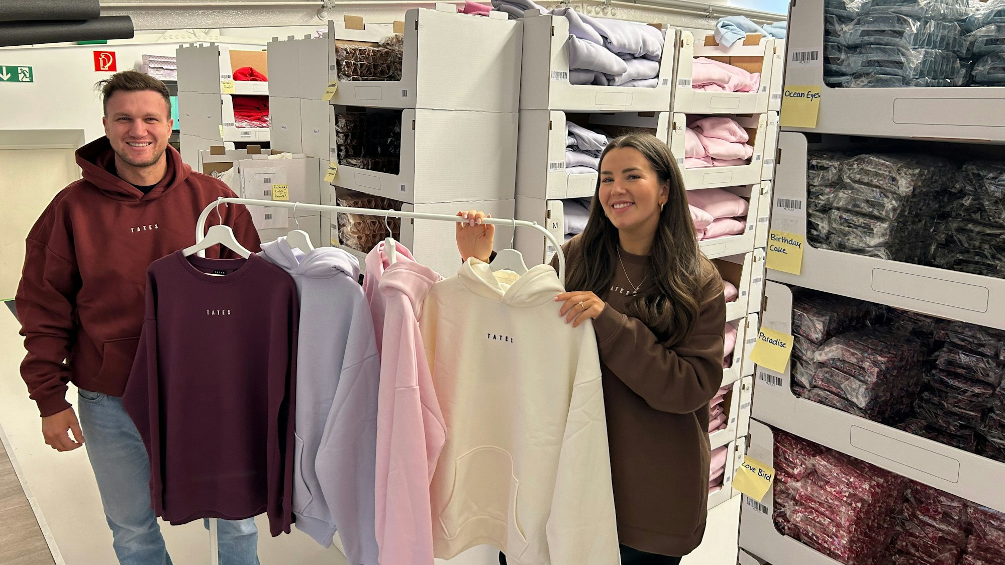 Mann und Frau mit Sweatshirts im Lager