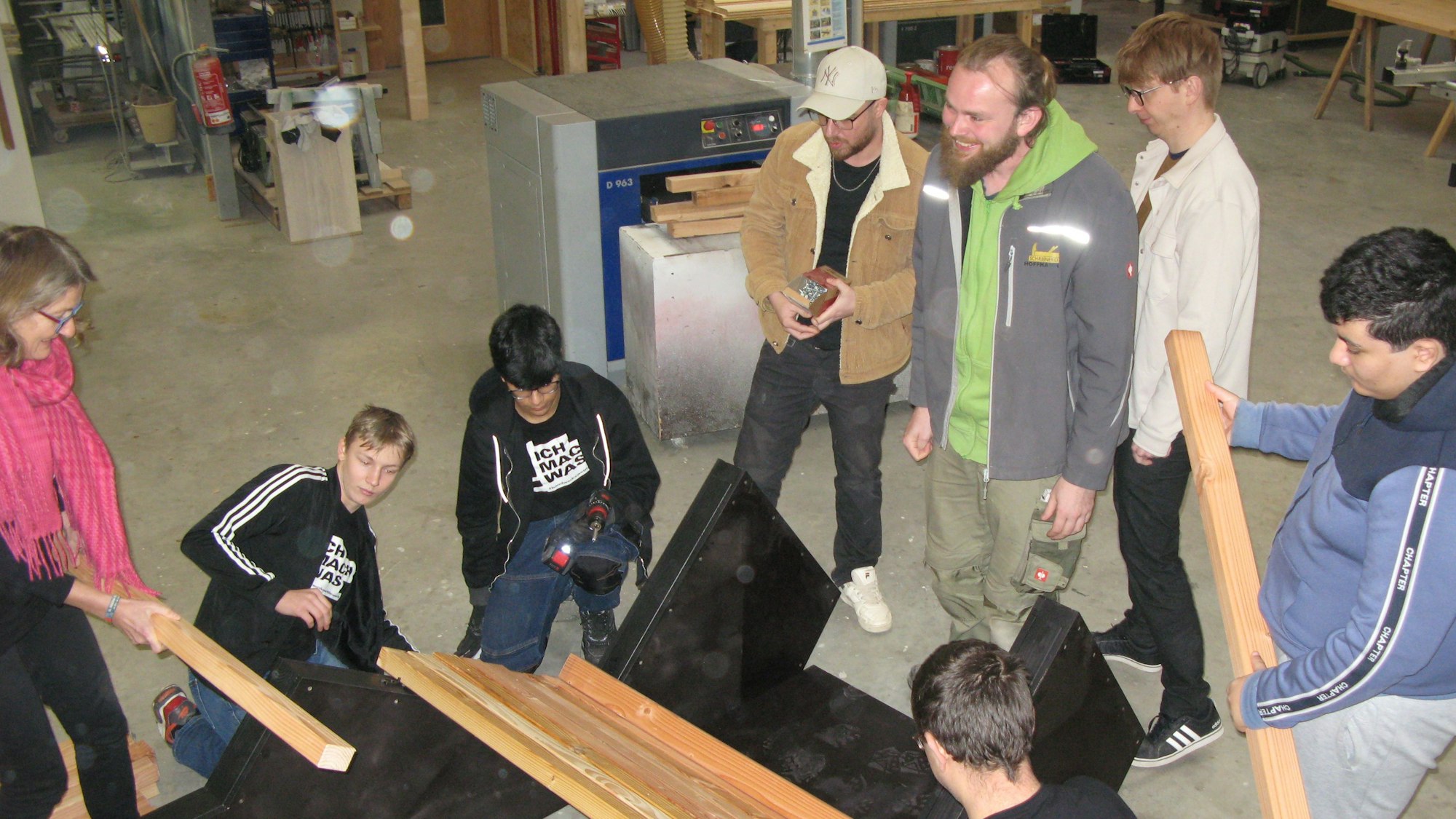 Jugendliche und Erwachsene mit Hölzern in einer Schreinerei.