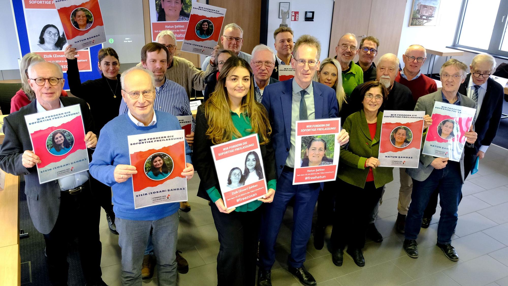 Archivbild vom 16.1.2025: Bürgermeister Dr. Hans-Peter Schick (vorne, 2.v.l.), Pinar Sahbaz und CDU-MdB Detlef Seif sowie Vertreter der Fraktionen von CDU, SPD, FDP, UWV und Grünen im Mechernicher Stadtrat halten Plakate mit den Porträts der Schwestern Zizik und Hatun Sahbaz aus Mechernich, die in der Türkei inhaftiert wurden.