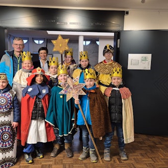 Zu sehen sind Kinder, die als Könige verkleidet sind, und zwei Erwachsene.