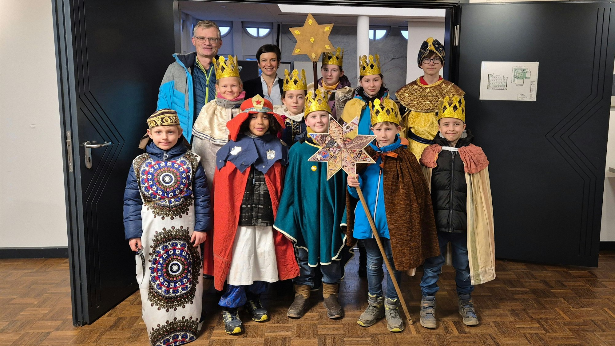 Zu sehen sind Kinder, die als Könige verkleidet sind, und zwei Erwachsene.
